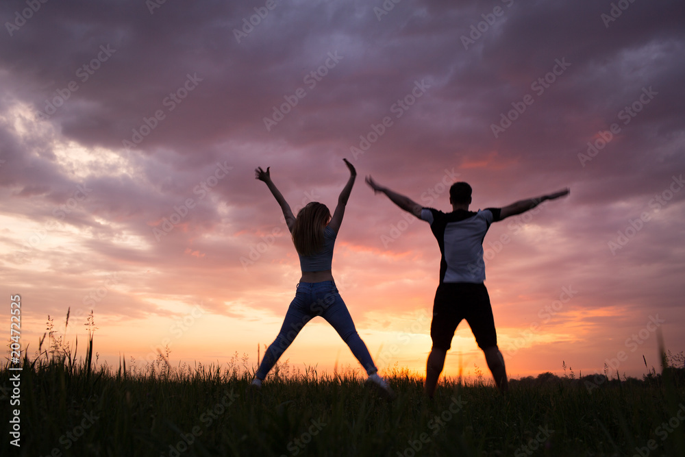 Silhouette of a young couple on sunset sky Silhouette of a young couple on sunset sky