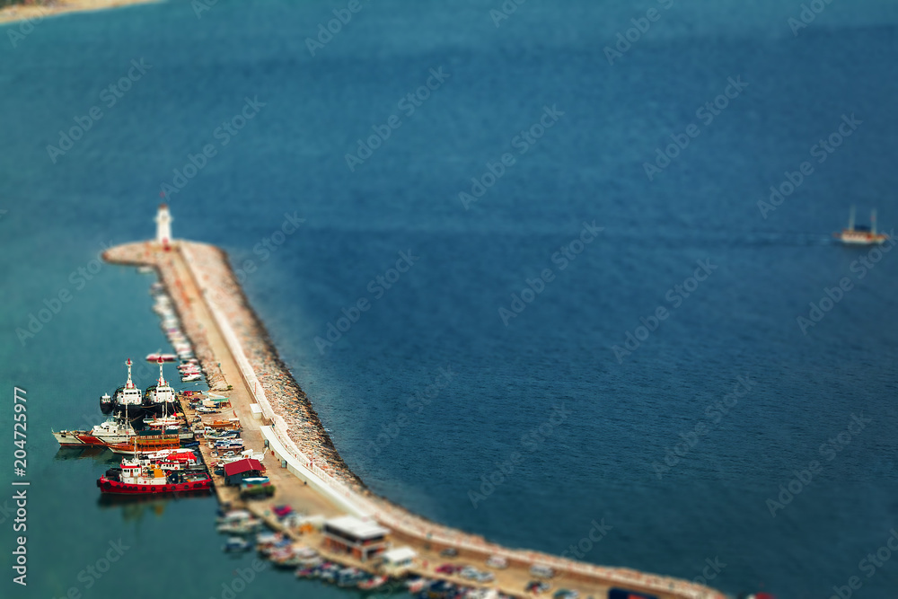 large pier with lighthouse situated on it, surrounded by ships and boats .view from a top. free space for text