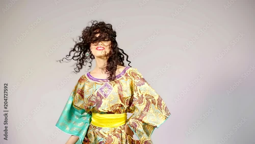 woman is wearing traditional gown is dancing in white wall background in studio woman is wearing traditional gown is dancing in white wall background in studio