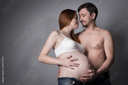 Husband and pregnant wife on gray background