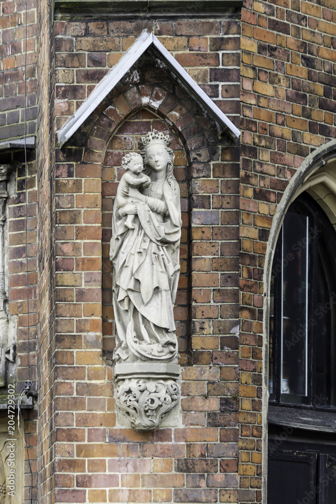 Obraz premium Detail of a brick cathedral in the Gothic style. Carved figure of the Virgin Mary on the side facade. St.Mary Magdalene Church.Wroclaw,Poland.