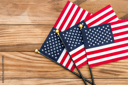 Three small american flags on wooden background. Top view. Copy space.