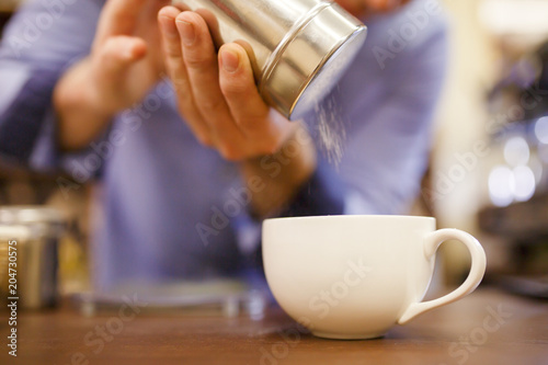 Photo of barista man pouring sugar into cup of coffee