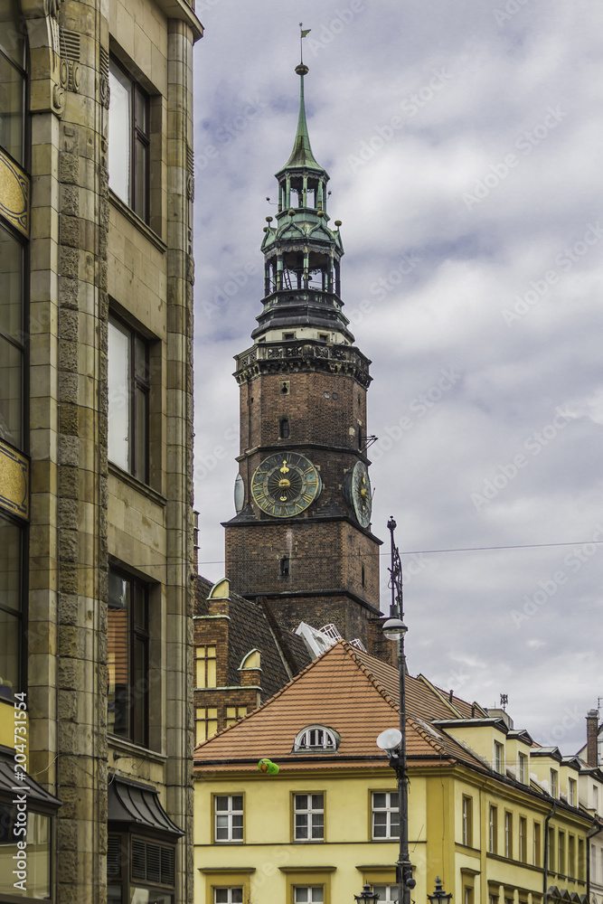 Brick tower with a tower clock. Part of the medieval Town Hall. Mixed style of architecture - Gothic and Baroque. The city of Vroslav, Poland.