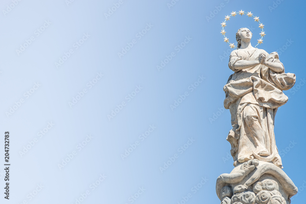Statue of praying lady at Marian Column or Holy Trinity at Hradcanske Square for bubonic plague epidemics in Prague, Czech Republic Statue of praying lady at Marian Column or Holy Trinity at Hradcanske Square for bubonic plague epidemics in Prague, Czech Republic