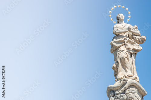 Statue of praying lady at Marian Column or Holy Trinity at Hradcanske Square for bubonic plague epidemics in Prague, Czech Republic