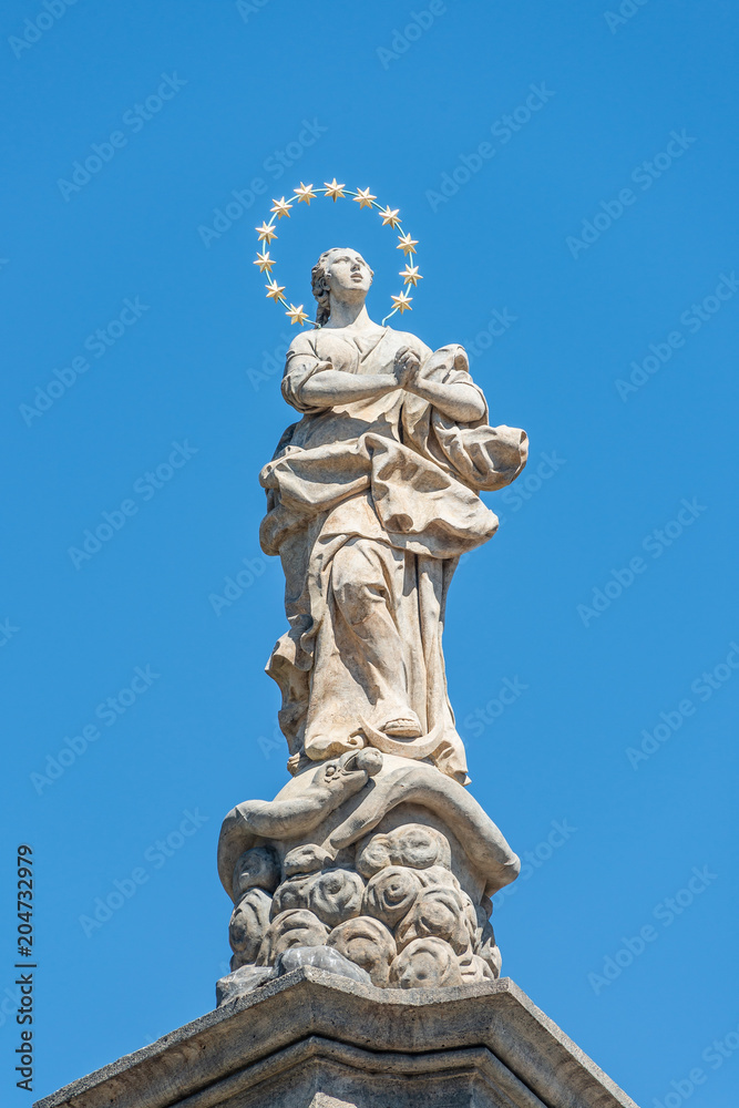 Statue of praying lady at Marian Column or Holy Trinity at Hradcanske Square for bubonic plague epidemics in Prague, Czech Republic