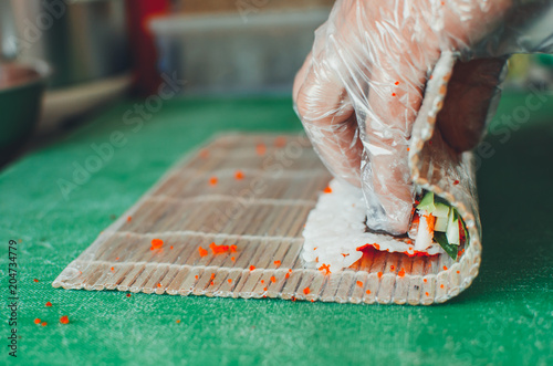 professional chef, chef the process of making sushi rolls, spins bamboo Mat and cut slices photo