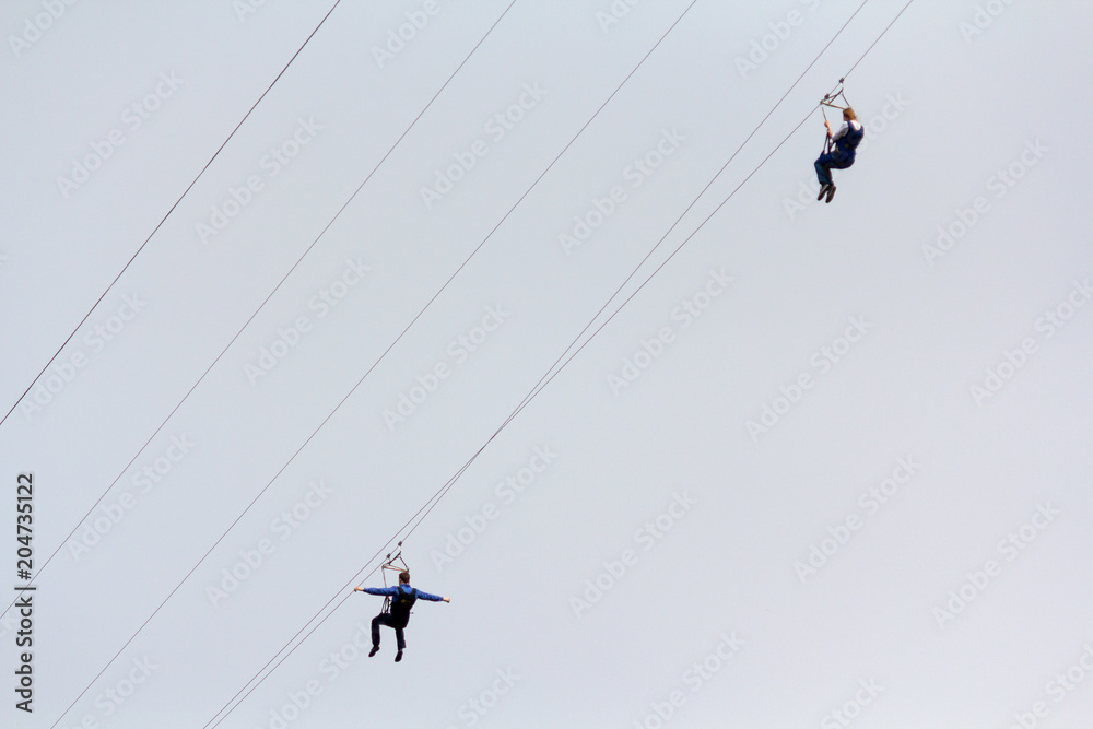 Woman and a man descend on a rope against the sky. Extreme Sports