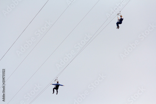 Woman and a man descend on a rope against the sky. Extreme Sports