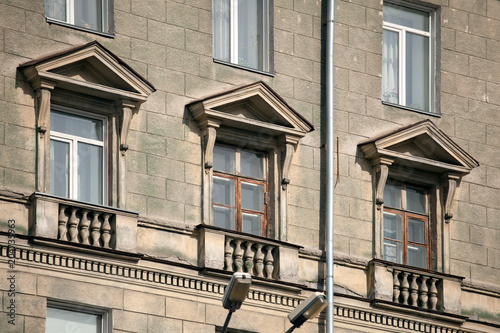 A close-up of old stone windows of a multistory building of Soviet construction. Facade of an old house