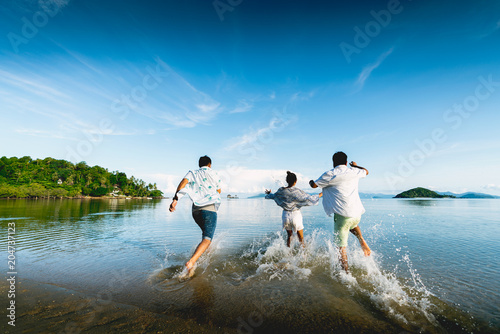 Asian family running on background of sunset beach and sea
