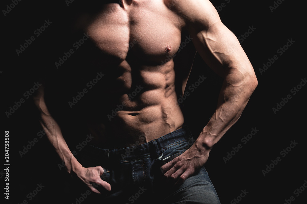 Fitness concept. Muscular and fit torso of young man having perfect abs, bicep and chest. Male hunk with athletic body on black background Fitness concept. Muscular and fit torso of young man having perfect abs, bicep and chest. Male hunk with athletic body on black background
