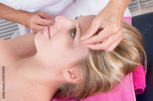 Closeup of girl hand performing acupuncture therapy on head at spa salon