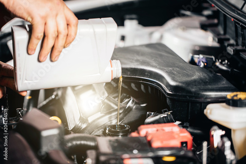 Pouring oil to car engine, close up photo