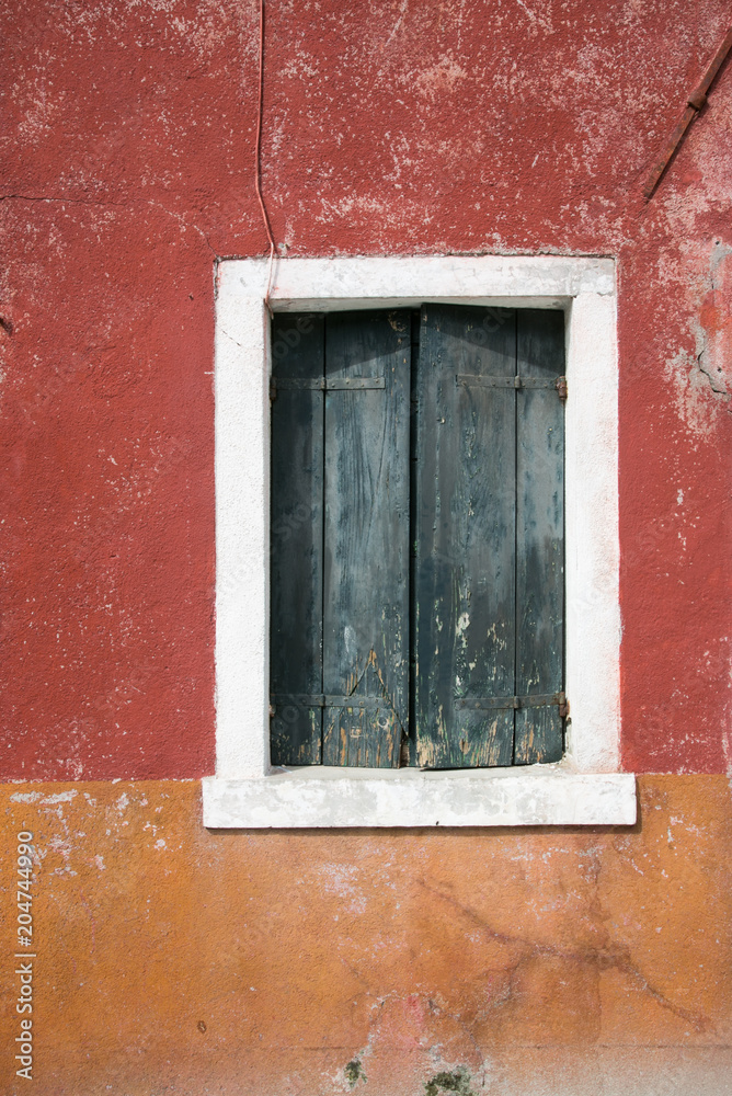 Verfallene Fensterläden vor rot oranger weisser Wand