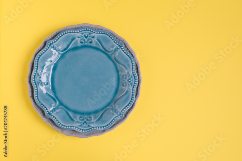 Two rustic plates on yellow background. Plates on left side of frame. Top view.
