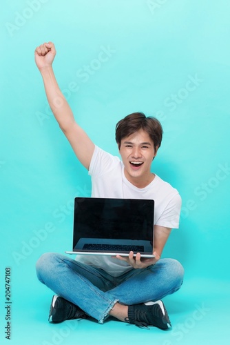A happy excited young asian man with a laptop  and celebrating success © makistock