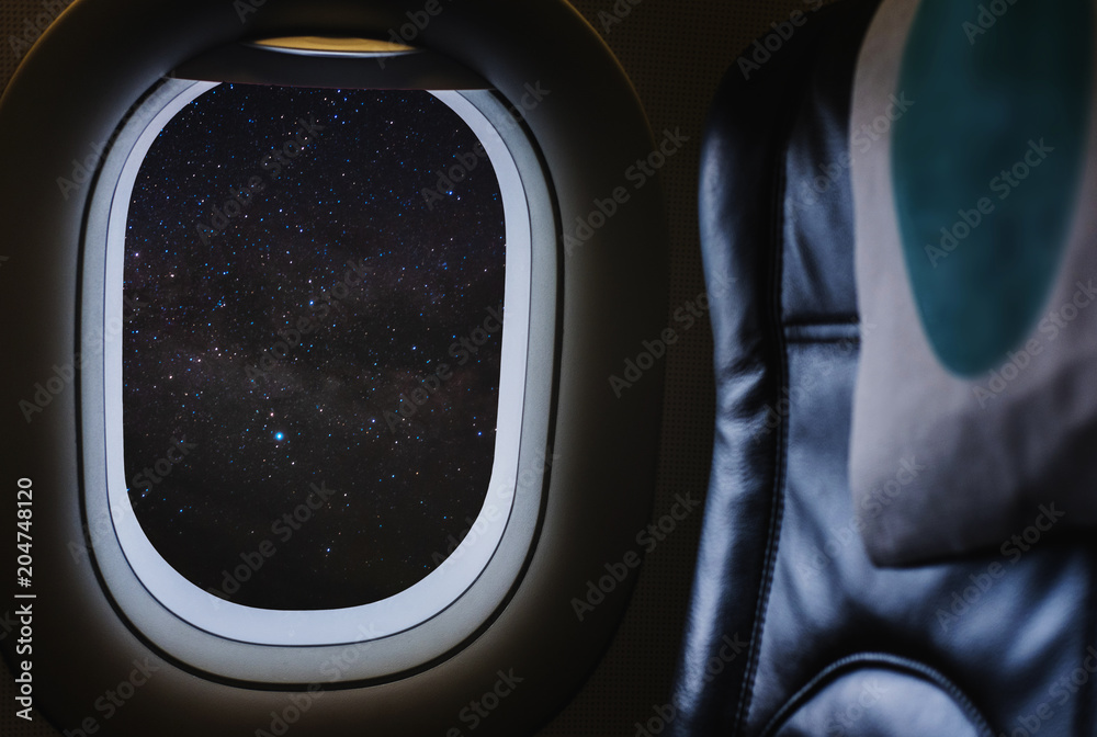 Fototapeta premium Travelling by air plane, looking through plane window enjoying beautiful night sky full of stars and milky way