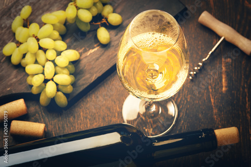 A glass of white wine and green grapes on wooden background photo