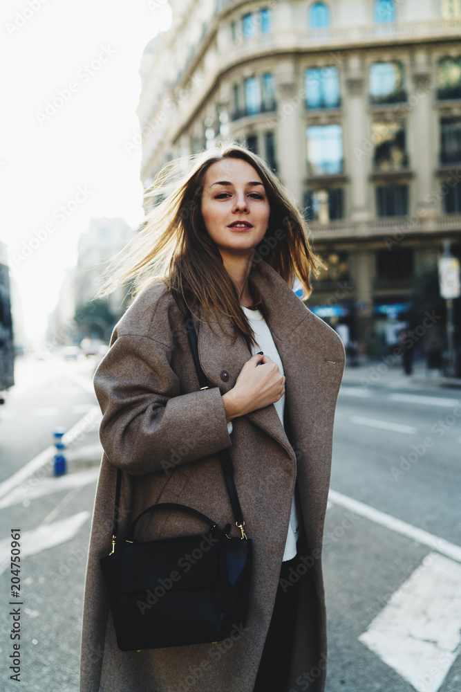 Photo in motion. Beautiful woman turning to the side while crossing the road in a city. Business woman hastens to the meeting. Hipster girl is on the cusp of to put out her hand to stop a taxi. Photo in motion. Beautiful woman turning to the side while crossing the road in a city. Business woman hastens to the meeting. Hipster girl is on the cusp of to put out her hand to stop a taxi.