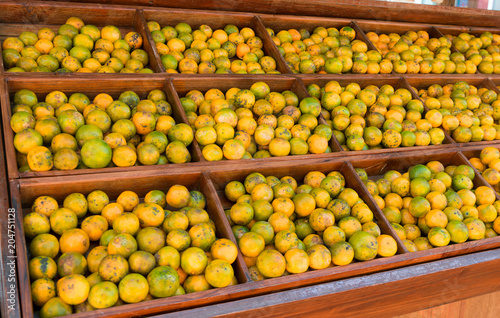 Many orange fruits are on the wooden boxes. Placed in the outdoor market.