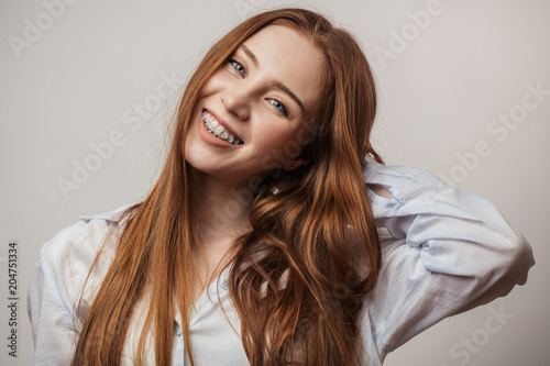 Happy young red-haired woman in braces smiling on white background looking at camera photo