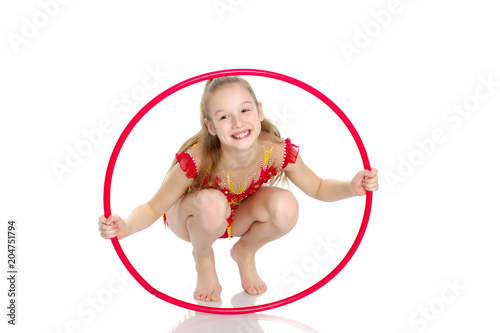 A girl gymnast performs an exercise with a hoop.