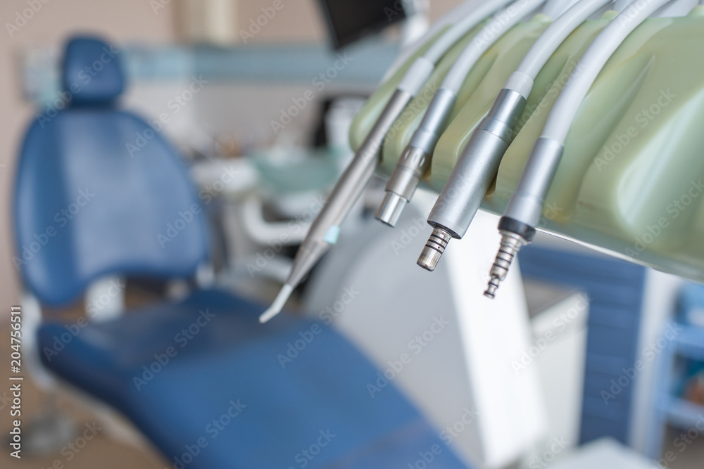 Fototapeta premium Close-up of various dental machines and tools with metal surface on stand of dental chair. 
