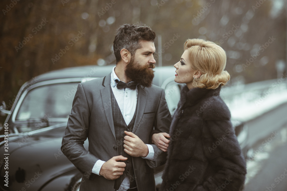Couple in love on romantic date. Bearded man and sexy woman in fur coat. Retro collection car and auto repair by mechanic driver. Travel and business trip or hitch hiking. Escort of girl by security.