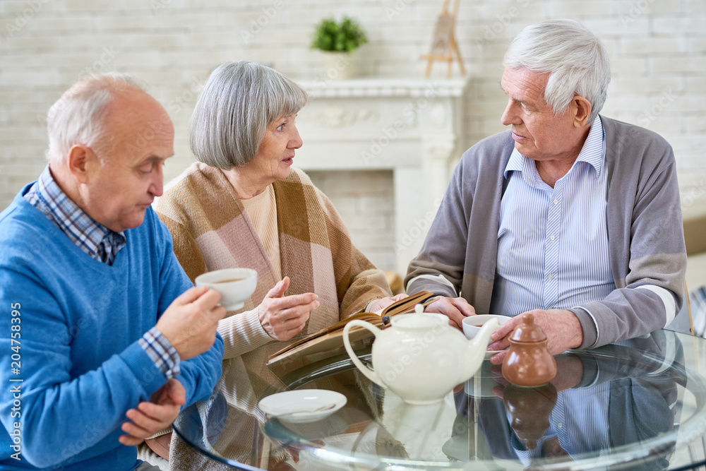 Group of elderly woman and men having teatime at table in cozy room of assisted living home. Group of elderly woman and men having teatime at table in cozy room of assisted living home.