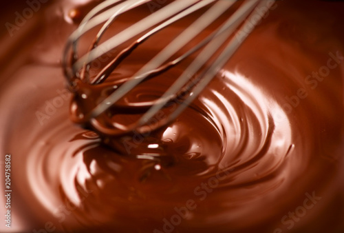 Chocolate. Mixing melted dark chocolate with a whisk. Closeup of liquid hot chocolate swirl. Confectionery