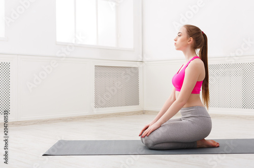 Woman training yoga in hero pose.