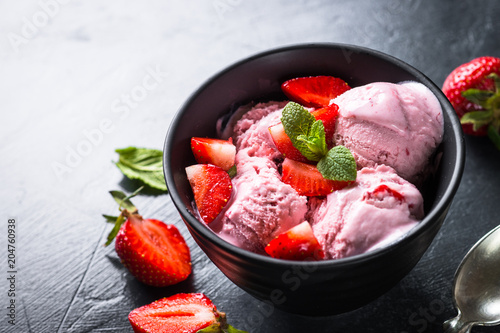 Strawberry ice cream with fresh berries on black.