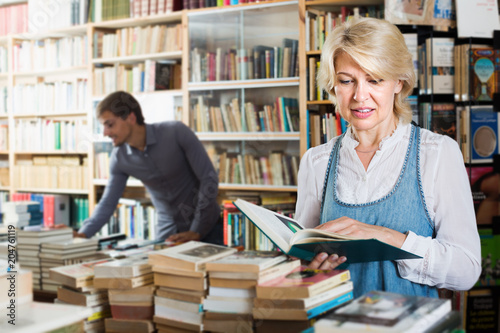 Mature woman looking at open book in book shop