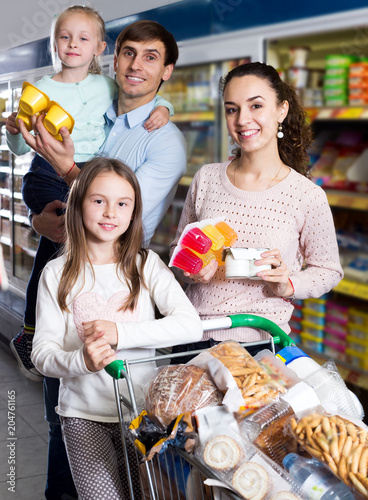 Parents with two kids buying fruit yoghurt
