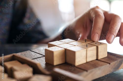 Closeup image of people playing wooden Tic Tac Toe game or OX game