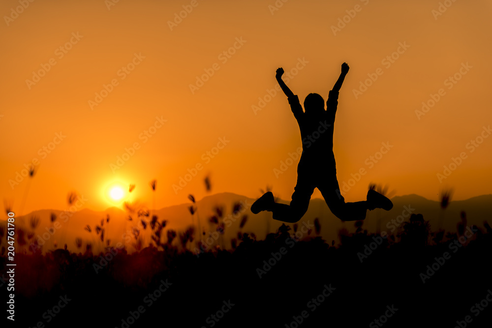 Happy woman jumping and sunset silhouette with copy space.