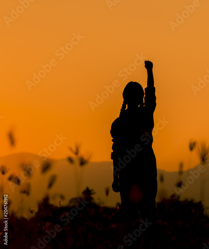 Принти на полотні Silhouette woman at sunset standing elated with arms raised up above her head