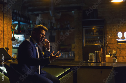 Angry businessman calling on the phone from the bar