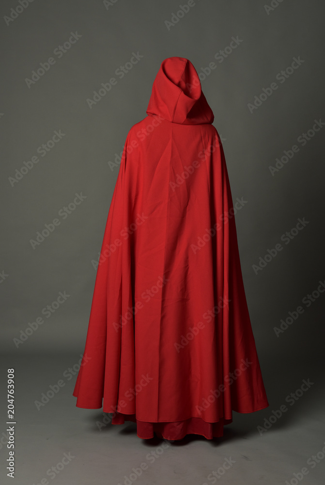 full length portrait of woman wearing red fantasy costume with cloak, standing pose on grey studio background.