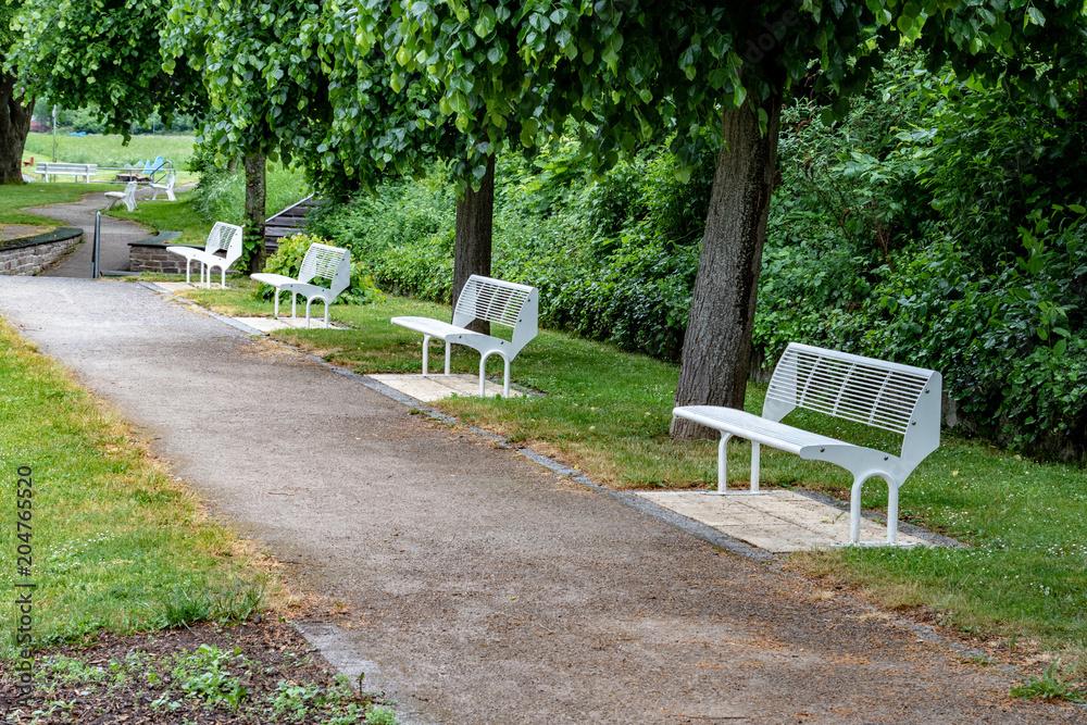 Several white metallic benches in a park in the city 