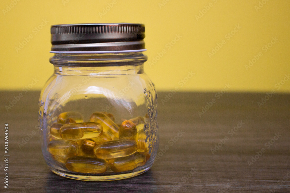 Cod liver oil omega 3 capsules in the bottle on the wooden table Cod liver oil omega 3 capsules in the bottle on the wooden table