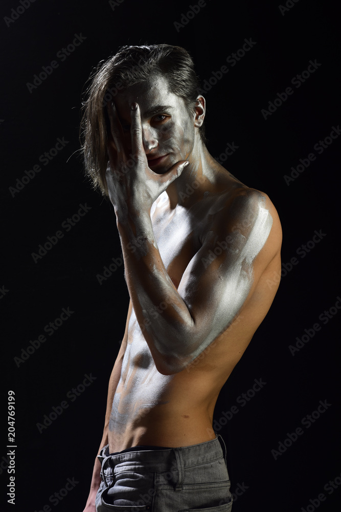 Man with nude torso covered with shimmering silver paint,