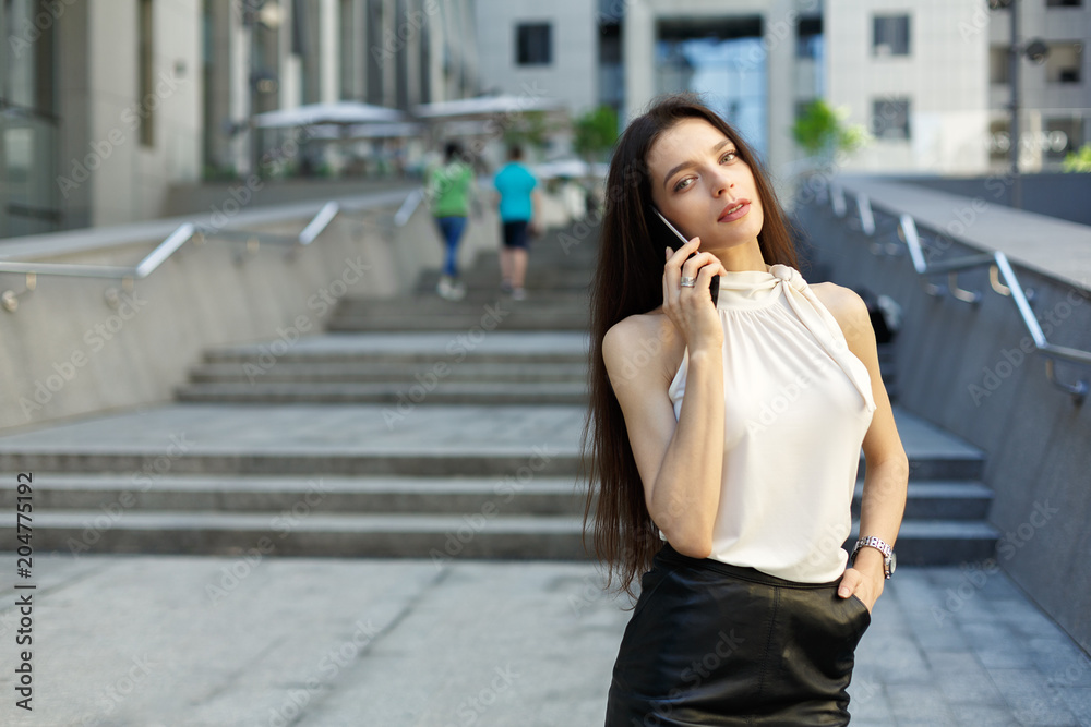 portrait of business woman with mobile phone on city and office center background.