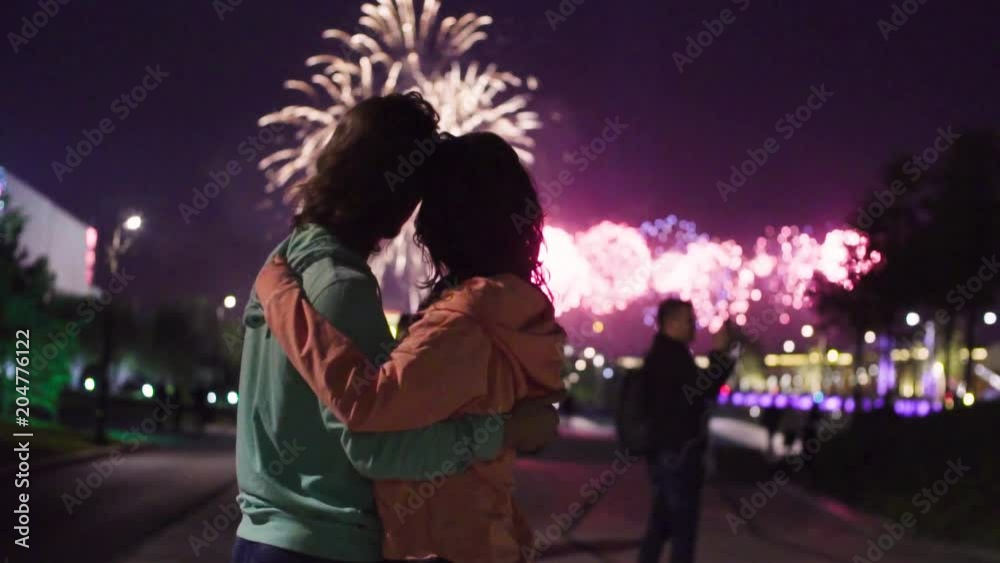Slow motion. Couple hugging and kissing on the background of fireworks in night city. Slow motion. Couple hugging and kissing on the background of fireworks in night city.
