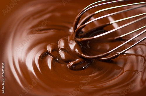 Chocolate. Mixing melted dark chocolate with a whisk. Closeup of liquid hot chocolate swirl. Confectionery