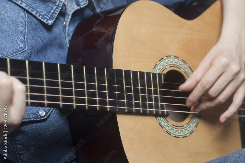 Fototapeta Young womans hands playing a acoustic classic guitar
