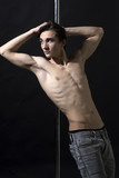 Young strong pole dance man with torso lean on pole.