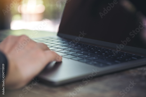 Closeup image of hands working and typing on laptop keyboard with blur background